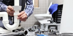 Plumber fixing plasting pipework under sink