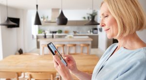 Mature Woman Using App On Digital Tablet To Control Central Heating Temperature In House