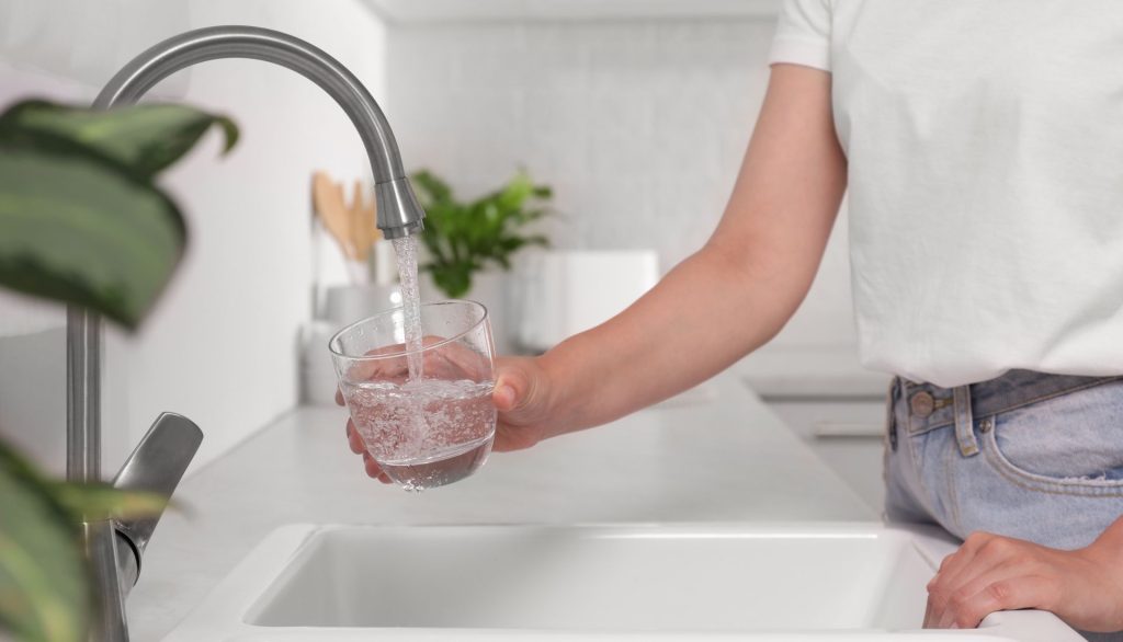 person running the tap and filling the glass up with water